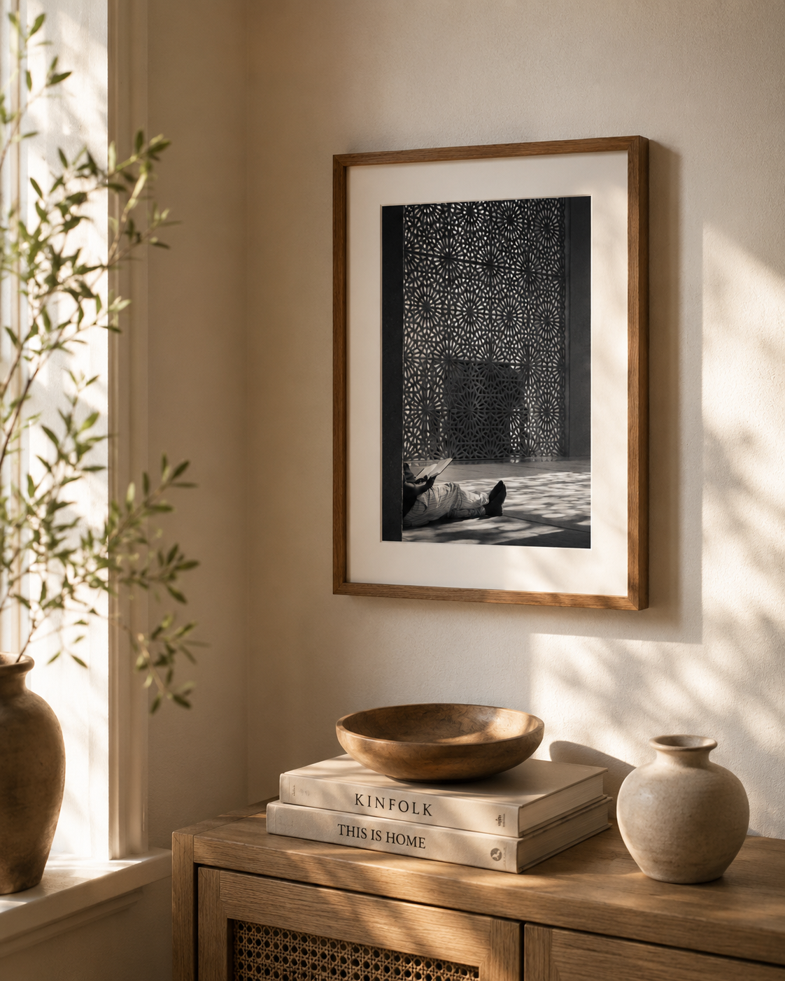 Framed artwork of a man reading areligious book in a mosque, on a wall with decor items on a wooden surface below
